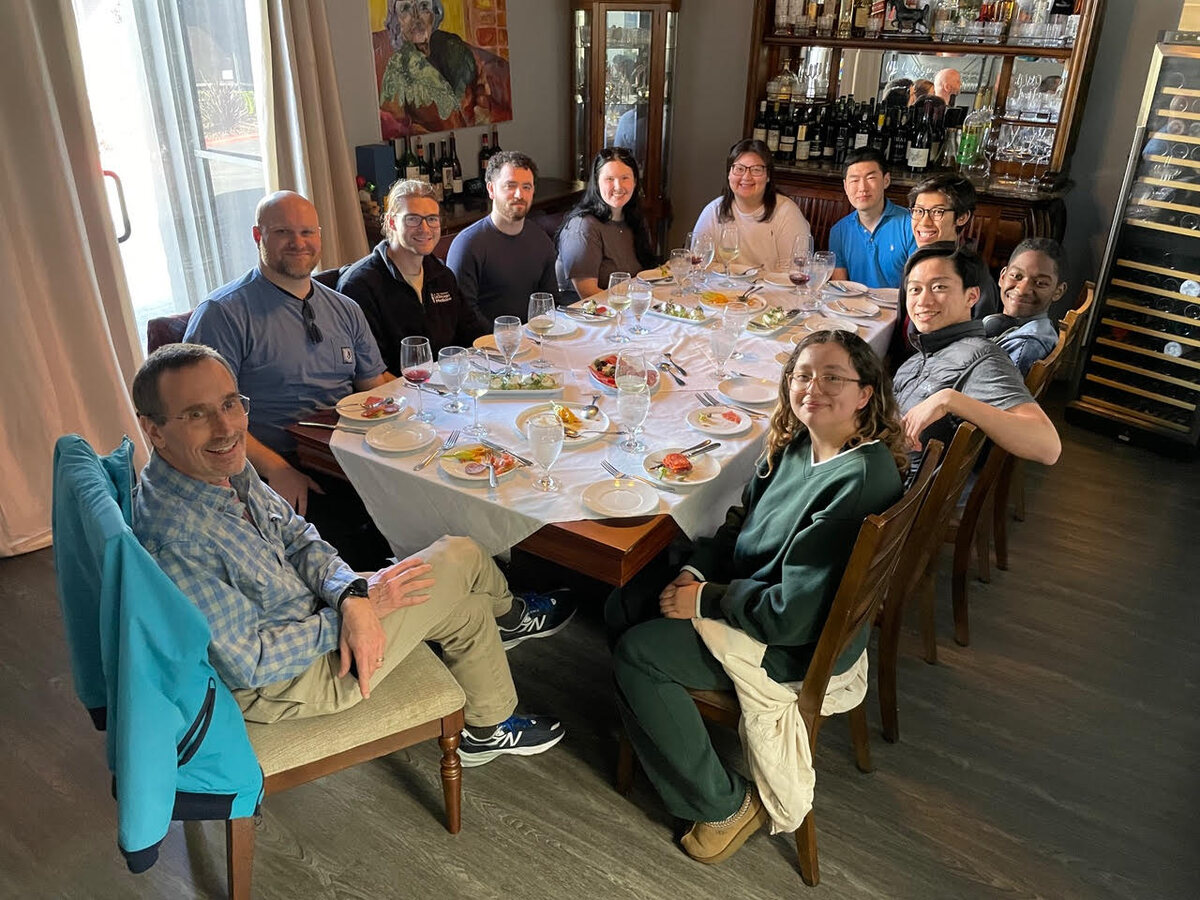 Nowick group members seated around a long table at a restaurant for a group lunch.